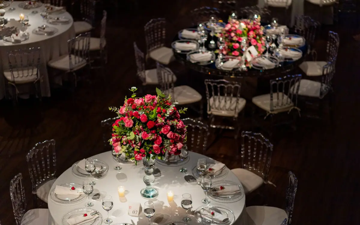 Wedding reception tables with pink floral centerpieces, candles and glassware, set before guests arrive